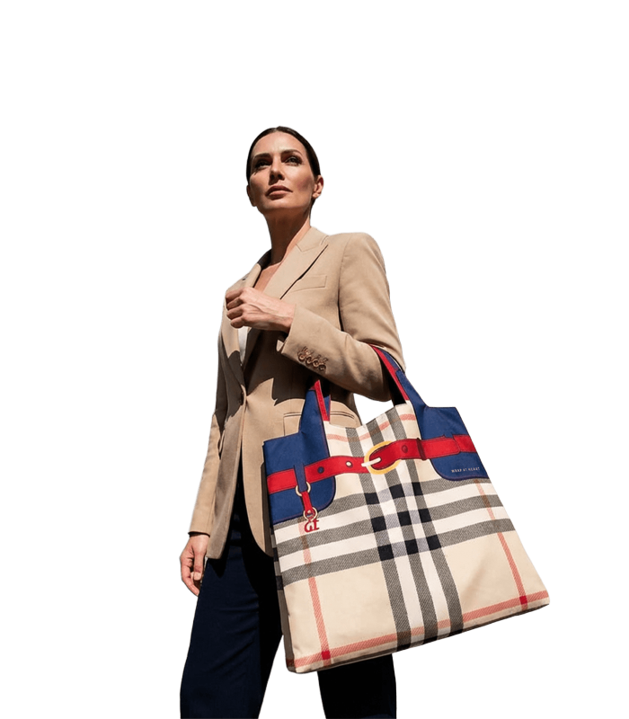 A woman in a beige blazer and dark pants carries the large Wrap at Heart tote bag, featuring a plaid design with red and blue accents in Athens.